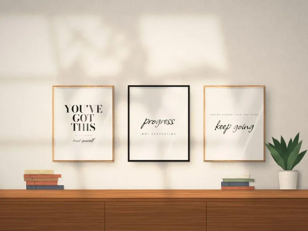 Three minimalist black and white Mindset quote prints framed above a sideboard